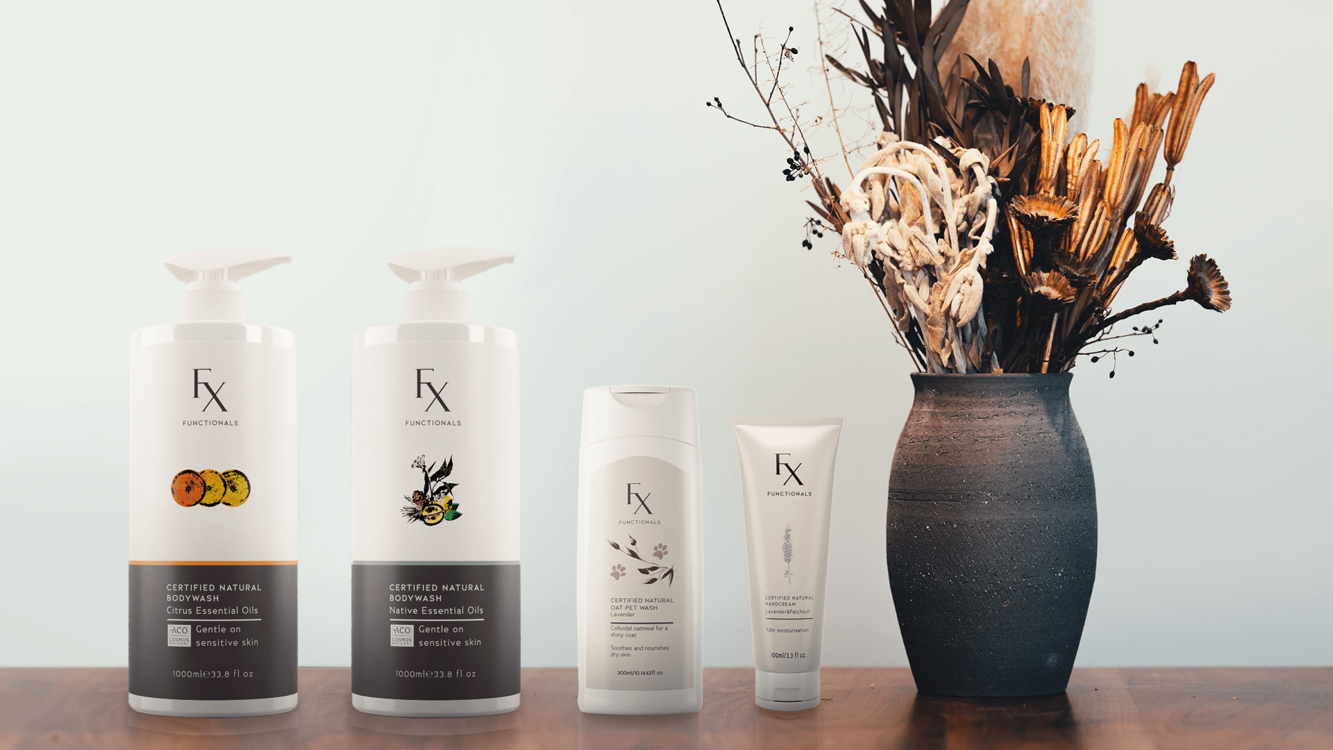 Functionals certified natural product range including: bodywash, dog shampoo and handcream on wooden table with dark ceramic vase filled with dried flowers